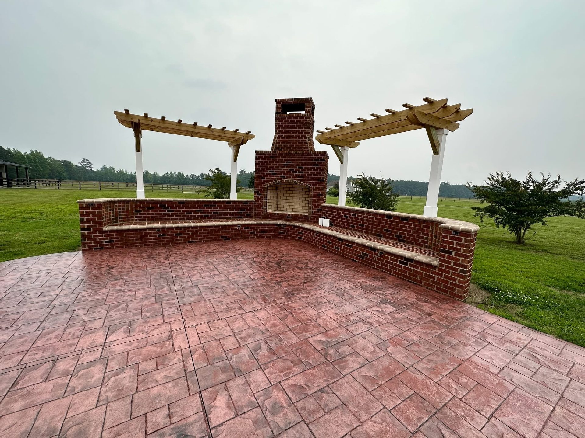 Custom brick outdoor fireplace, seat wall, and stamped concrete patio built by Complete Contracting Solutions LLC