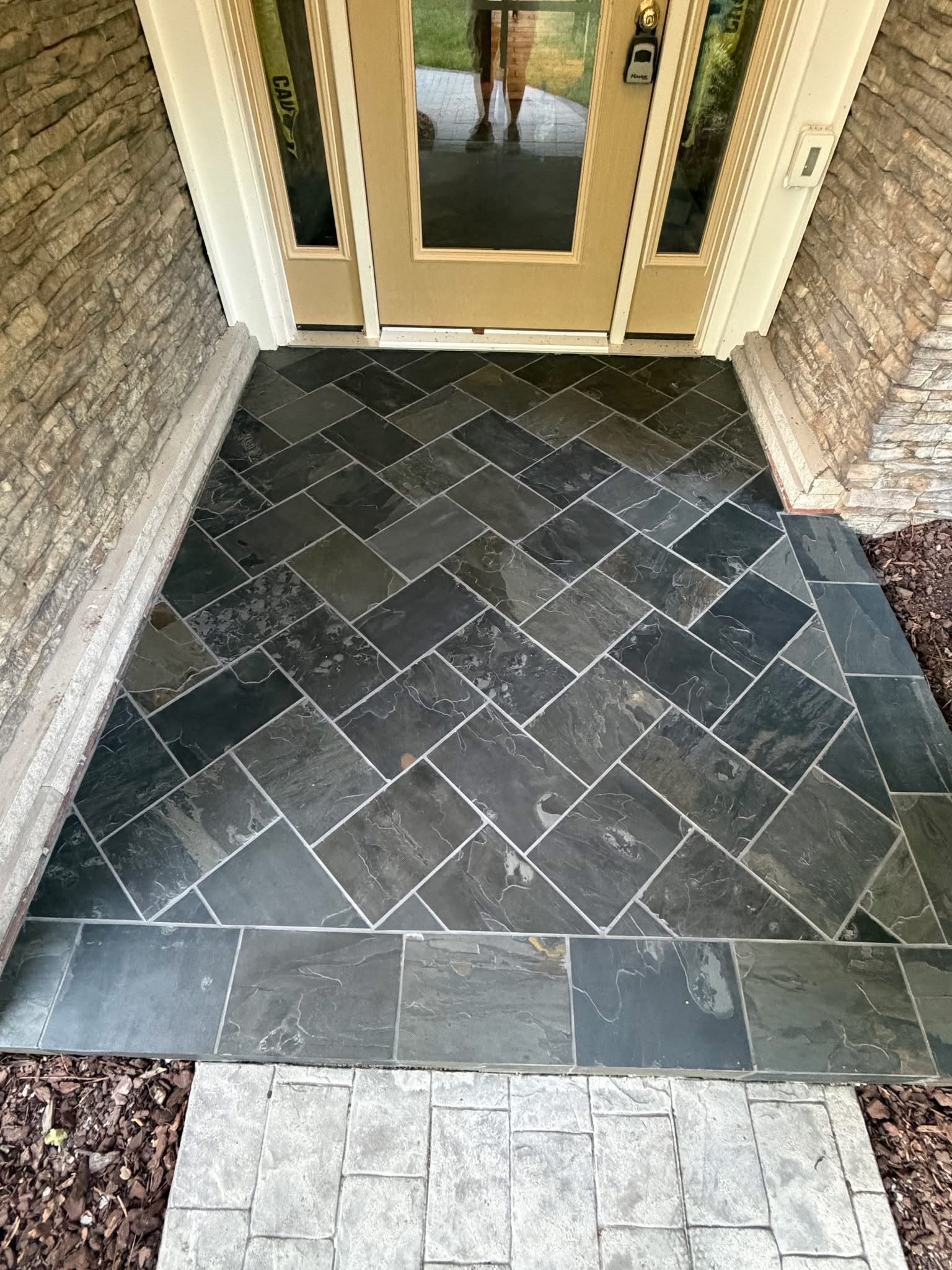 Slate herringbone tile front entry with stone veneer surround